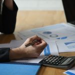 Start up business concepts,Accounting staff is summarizing the company budget.She uses a calculator and analyzes the data graph,Accounting concept